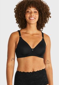 Svart bh med spetsdetaljer, med triangulär form, justerbara band, scallopkanter och en centrerad logotyp.