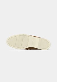 Suela de un zapato marrón de hombre con suela de goma beige, patrones de agarre texturizados, talla 45 y la marca Tommy Hilfiger.