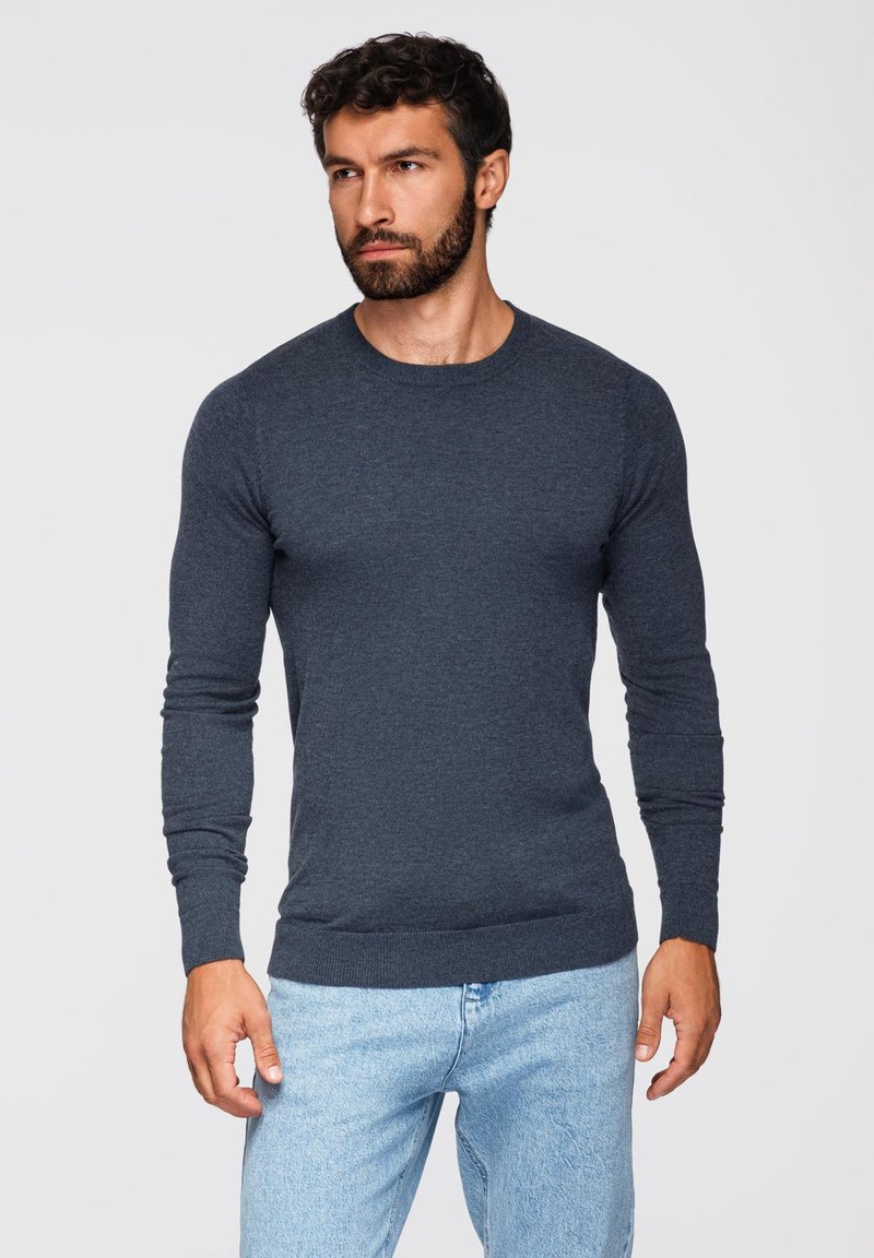 Maglione grigio scuro a maniche lunghe con scollatura a girocollo, realizzato in materiale morbido. Presenta polsini e orlo a costine, design aderente e texture liscia.