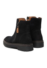 Botines de ante negro con detalles en cuero marrón, cremalleras laterales y suelas de goma texturizadas. Detalles cosidos alrededor de la suela.