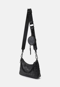 Bolsa preta com letras em relevo, de forma curva e acabamento texturizado. Apresenta um bolso circular destacável e alça ajustável.