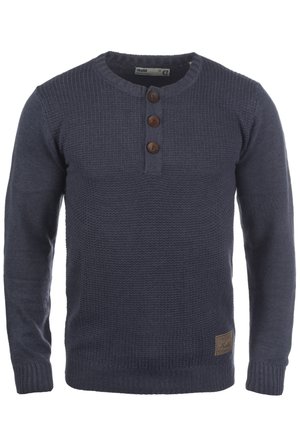 Navy knitted sweater with long sleeves, round neck, three brown buttons at the collar, and a ribbed hem. Features a branded leather patch.