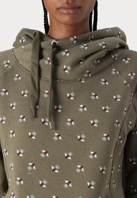 Sudadera con capucha en verde oliva que presenta pequeños pájaros estampados en rojo, blanco y verde azulado. Cierre con cordón y textura suave con mangas raglán.