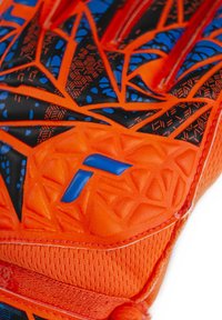 Bright orange soccer glove with black and blue geometric patterns, textured grip surface, and padded orange accents on the palm.
