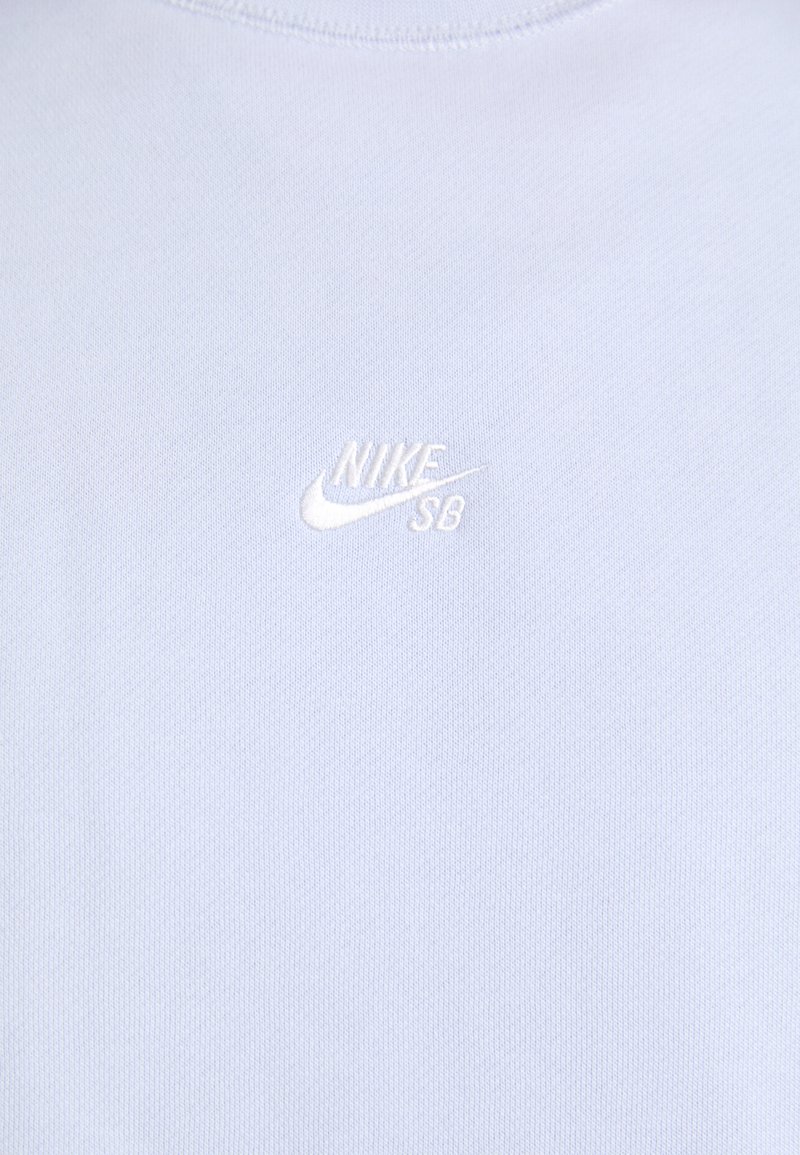 Jasnoniebieska bawełniana koszulka z krótkim rękawem, wyposażona w małe białe haftowane logo Nike SB na lewej piersi oraz okrągły dekolt z prążkowanym wykończeniem.