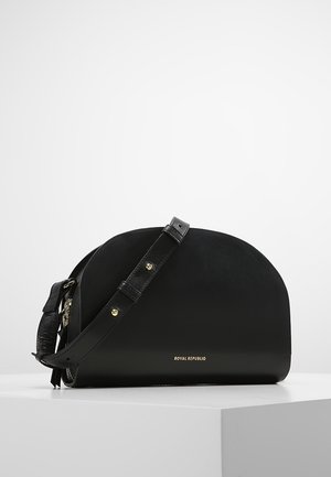 Zwarte halfmaanvormige crossbodytas met verstelbare riem en goudkleurige hardware, geplaatst op een witte ondergrond.