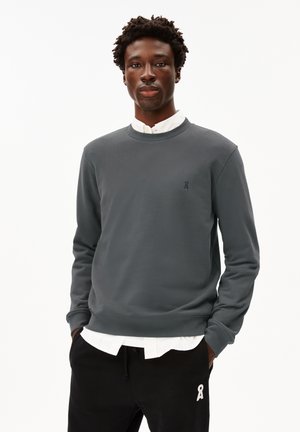 Grey sweatshirt made of cotton, featuring a crew neck, long sleeves, and a small logo on the chest. Paired with black drawstring pants.