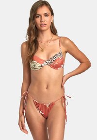 Ensemble de bikini à motifs mêlant des imprimés floraux et animaliers, dans des teintes de corail et de beige, avec des liens ajustables sur les côtés du bas.
