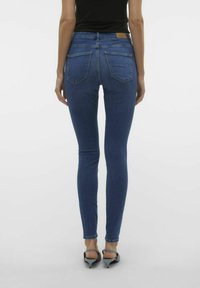 Sötétkék farmer skinny farmernadrág, magas derekú, öt zsebbel és egy barna bőrcímkével a hátsó deréknál.
