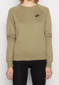 Khaki-coloured sweatshirt with a round neckline, raglan sleeves, and ribbed hem and cuffs. It has a black Nike logo on the upper left chest. The fabric has a soft texture.