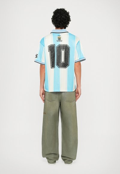 Light blue and white striped jersey with black number 10, collar, and logo on back. Paired with baggy olive green pants.
