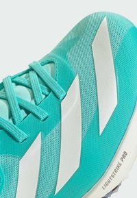 Scarpa da ginnastica turchese con una tomaia testurizzata, strisce bianche diagonali e un'etichetta "LIGHTSTRIKE PRO" visibile sulla suola.