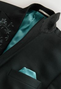 Schwarzer Blazer mit einem türkisfarbenen Satinfutter und einer Tasche. Verfügt über florale Stickereien am linken Revers und einen strukturierten Kragen.