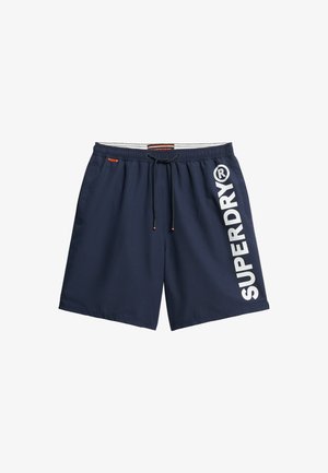 Navy swim shorts made of lightweight fabric, featuring an elastic waistband with drawstring and large white "SUPERDRY" logo along the side.