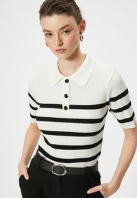 Gestreiftes Polohemd in Weiß mit schwarzen horizontalen Streifen, gerippter Textur, kurzen Ärmeln und drei schwarzen Knöpfen am Kragen.