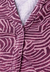Top de manga corta con un patrón zigzagueante texturizado en tonos rosa y morado, con un escote en V y detalles de costura en contraste.