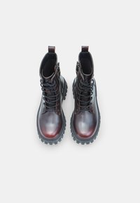 Nahkased säärekingad läikiva tumepunase viimistlusega, ümarad varbad, nööbid ees, sääre kõrgus ja robustne must kummitald.