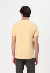 Short-sleeve t-shirt in soft, light yellow cotton. Classic crew neckline, plain design with no visible patterns or accents.