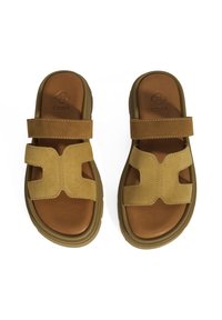 Bruine suède slide-sandalen met dubbele banden en een kruisontwerp. Rubberzool met een gladde leren binnenkant. Fabrikantlogo diep in de binnenkant gedrukt.