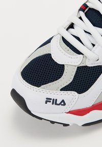 Granatowe siatkowe sneakersy z białymi skórzanymi akcentami, szarymi detalami i czerwonymi wyróżnikami. Posiadają teksturowany materiał i wyraźne logo Fila.