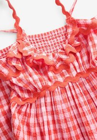 Rood en roze geruite mouwloos jurkje met ruches, elastische smocking bovenaan en geplooide textuurstof.