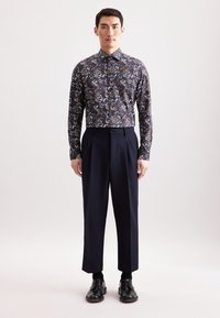 Heren bloemen overhemden in donkerblauw, met ingewikkelde patronen. Gecombineerd met op maat gemaakte zwarte broek en klassieke zwarte schoenen.