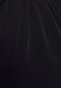 Tecido preto com uma textura suave e um leve brilho. Apresenta pregas na cintura, criando dobras suaves no material.