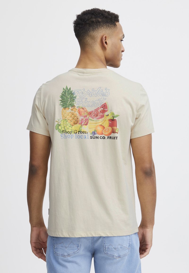 Beige bomulds T-shirt med et farverigt frugt grafik på ryggen, der har teksten "Florida's Finest" og "Shop local SUN CO. FRUIT."