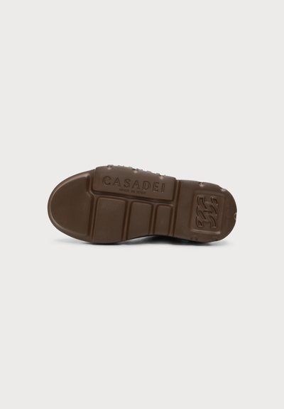 Semelle de chaussure en caoutchouc marron avec grip texturé, motifs rectangulaires et "CASADEI MADE IN ITALY" embossé au centre.