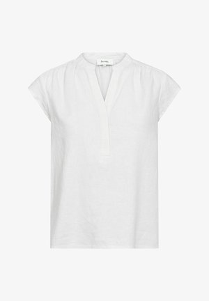 Blouse en lin blanc avec un col montant, des manches courtes type cap et une patte de boutonnage verticale. Présente des détails de fronces aux épaules.