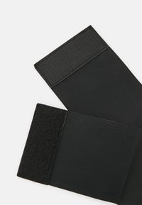 Black fabric straps with textured Velcro closures. Smooth surface with a flat shape, designed for secure fastening.