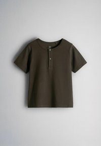 Chemise marron foncé à manches courtes avec un col rond et une patte à deux boutons, présentée à plat sur un fond gris clair.