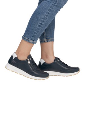 Marineblauwe leren sneakers met een witte hielaccent, ritssluiting, ronde neus en een getextureerde zool. Denim jeans met opgerolde mouwen worden getoond.