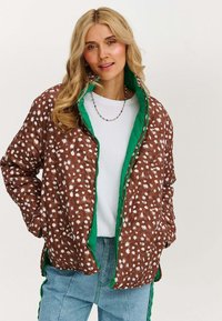Brązowa pikowana kurtka w białe kropki, z zielonym podszewką i zamkiem, luźny krój, z bocznymi kieszeniami i casualowym kołnierzem.