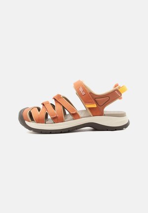 Udendørs sandal med orange justerbare remme, polstret sål, gummisål og gul træksløjfe på hælen.
