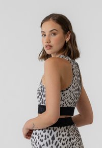 Løverprikket tanktop med et sort elastisk bånd. Glatt materiale, tettsittende design, rund hals og detaljer langs kantene.
