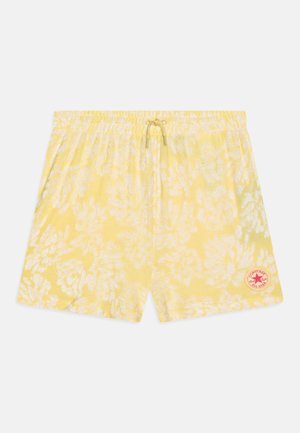 Shorts de bain jaunes avec un motif floral blanc, taille élastique, fermeture par cordon de serrage et une bande rouge avec logo sur le côté inférieur droit.