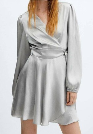 Woman wearing a light gray satin wrap dress with long puffed sleeves and a flared skirt, standing against a plain white background.