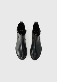 Botas de cuero negras hasta el tobillo con un acabado suave, paneles laterales elásticos, cierre de cremallera y un diseño minimalista.