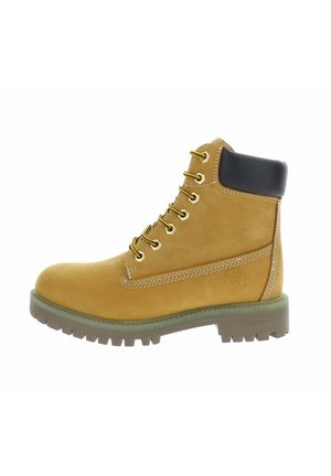Bota de trabajo de cuero tostado con cuello acolchado negro en el tobillo, cordones amarillos y negros, y suela gruesa de goma con profundas ranuras.