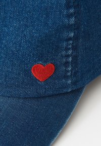 Dunkelblaue Denimkappe mit einem kleinen, roten, gestickten Herz auf dem vorderen Panel in der Nähe des Schirms.