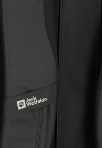Zwarte rugzak met een textuurstof, verstelbare banden en een logo patch met de naam "Jack Wolfskin" in het wit.
