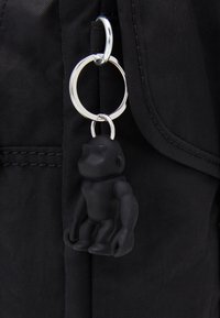 Sort stof nøgleholder med en gorilla figur, fastgjort til en sølv metalring på en tekstureret rygsækoverflade.