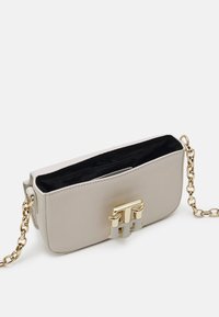 Lichtgrijze neplederen tas met een goudkleurige sluiting, kettinghengsel en een open bovenkant die een zwarte binnenkant onthult. Compact rechthoekig formaat.