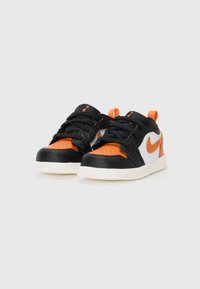 Black and orange sneakers with white accents, featuring a smooth leather upper, textured overlays, black laces, and a white rubber sole.