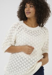 Sweter dziany w kolorze kremowym z luźnym wzorem o otwartej strukturze. Posiada szeroki dekolt, krótkie rękawy oraz ściągacz u dołu i przy rękawach.