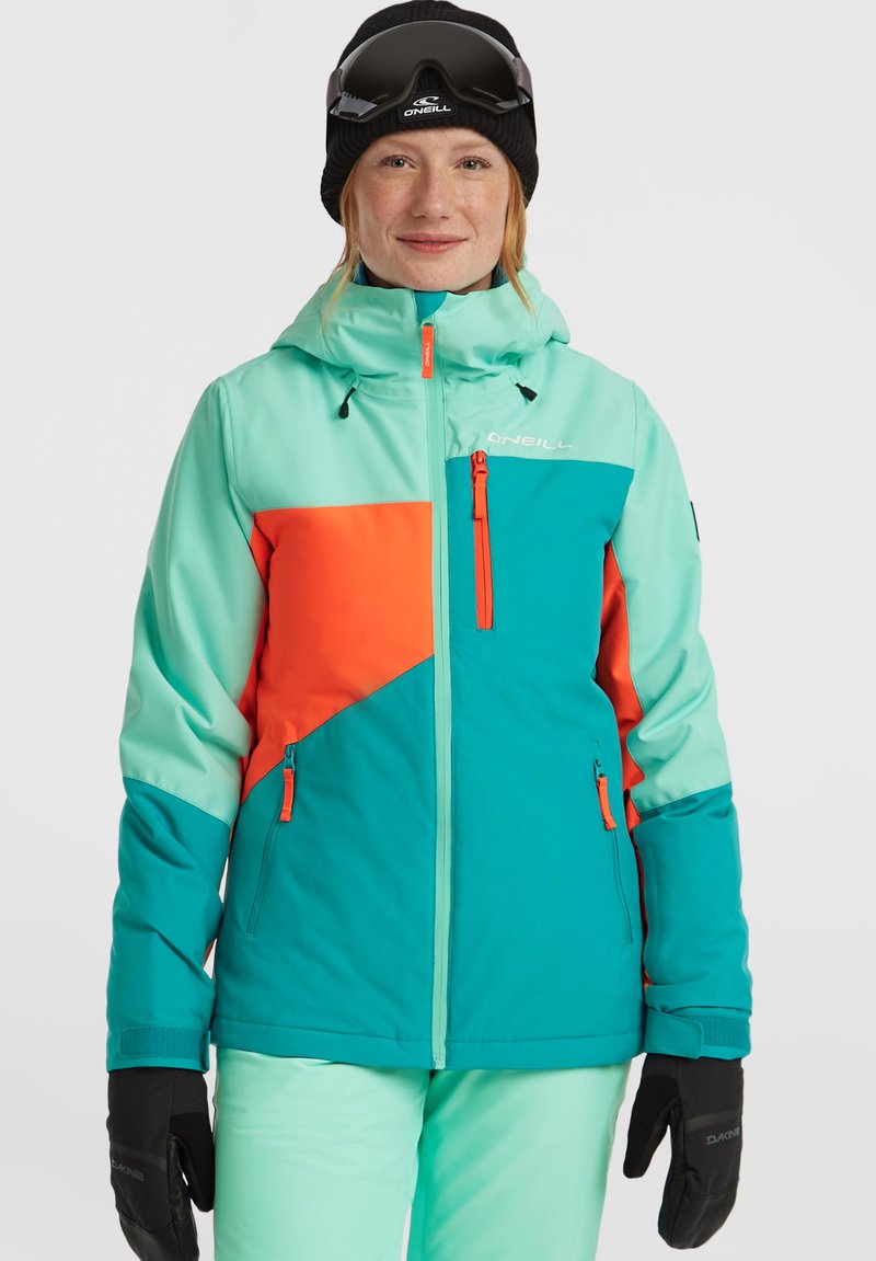 Teal en oranje skijack met schuine kleurvlakken, ritszakken, verstelbare capuchon en zwarte handschoenen. Gladde stof en sporty ontwerp.