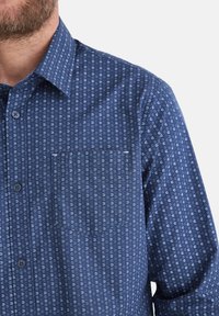 Blaues Hemd mit Knopfleiste, das ein geometrisches Muster mit hellblauen Akzenten, einer Brusttasche und einer strukturierten Stoffoberfläche aufweist.