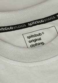 Light gray cotton t-shirt with a ribbed collar. Label reads "spitzbub original clothing." Black tag features "spitzbub STUDIOS."