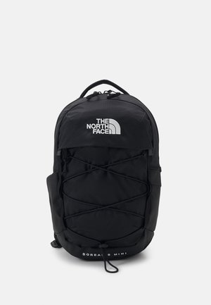 Zwarte rugzak met een gestroomlijnd ontwerp, voorzien van elastische koorddetails, gewatteerde riemen en het logo "THE NORTH FACE" aan de voorkant.
